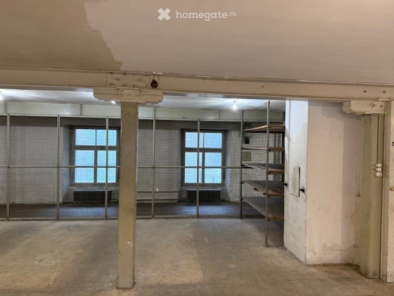open room, metal bars, windows, shelves, white walls, central beam
