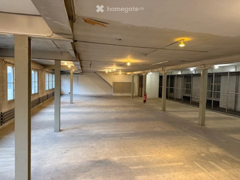 Warehouse space, wide, clean floor, bare brick walls, metal beams, metal grates