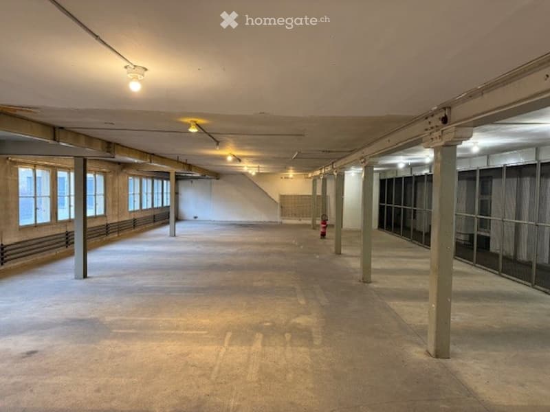 large open parking space, concrete floor, windows, fire extinguisher, pillars