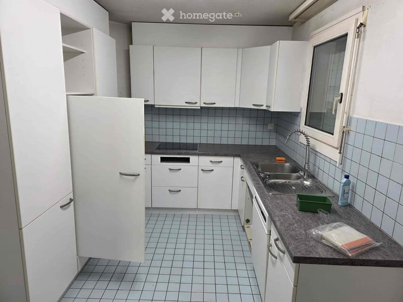 Spacious kitchen with white cabinets, tiled backsplash, granite countertops, and a dishwasher. The kitchen also includes a refrigerator and sink.