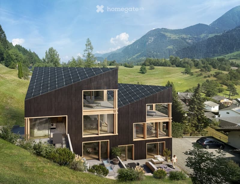 Modern two-story house with dark wooden exterior, large windows, solar panels on the roof, surrounded by a green landscape with mountains in the background.