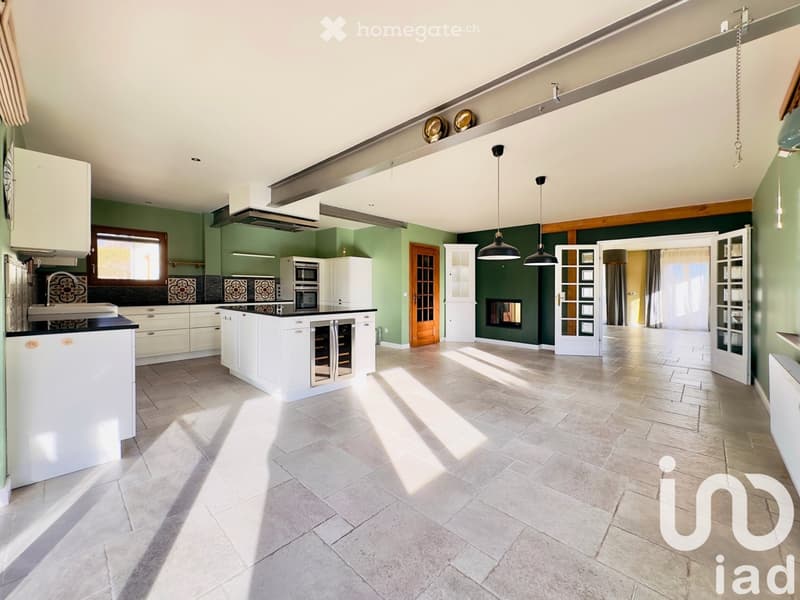 open plan kitchen, white cabinetry, granite countertops, modern appliances, green walls, fireplace, pendant lights, wide open room