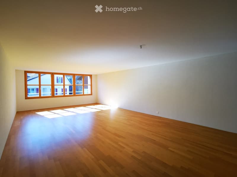 Spacious room with large windows, hardwood flooring, and bright, natural lighting.