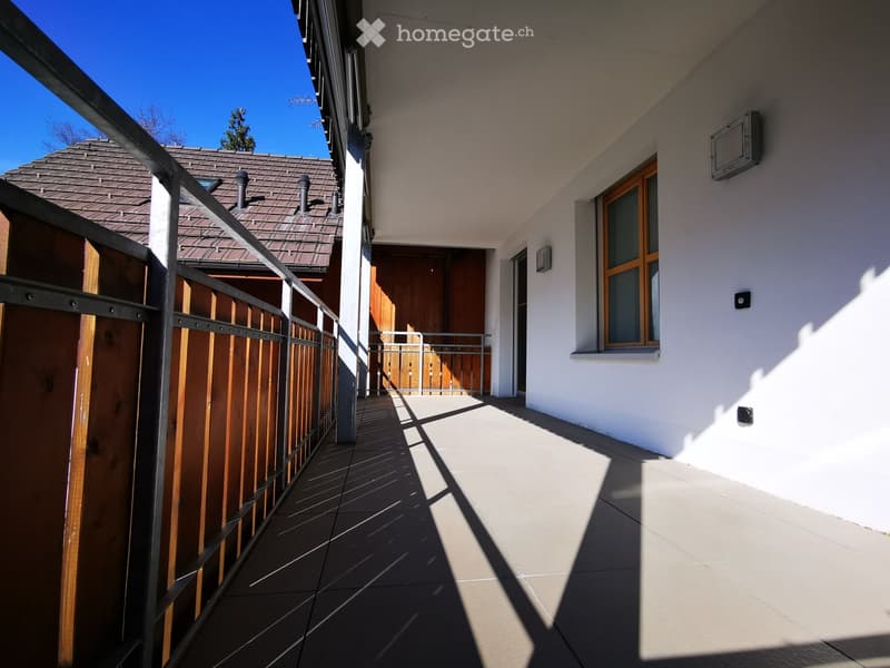 2-story house with a wooden balcony, tiled roof, and white exterior walls