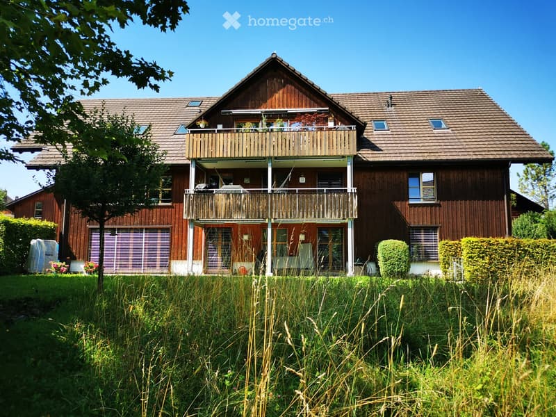 2 story wooden house with balconies, surrounded by trees and tall grass