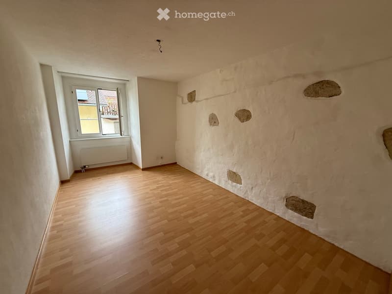 Empty room, wooden floor, white walls, small window, electric outlets, built-in heater