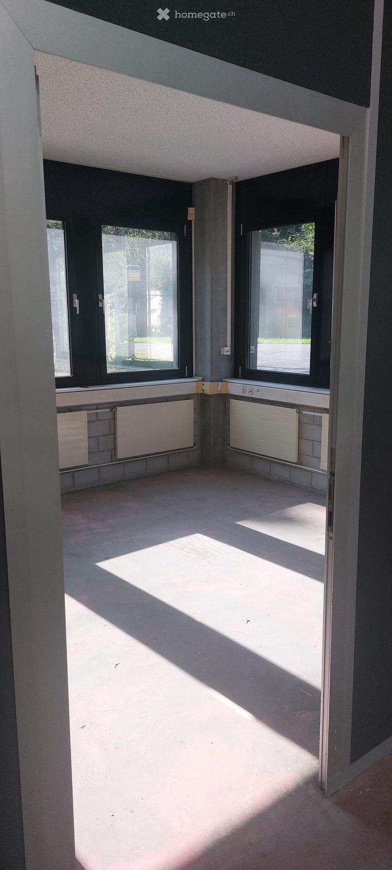 Empty room, white walls, gray flooring, black windows, window sills with built-in white radiators and outlets.