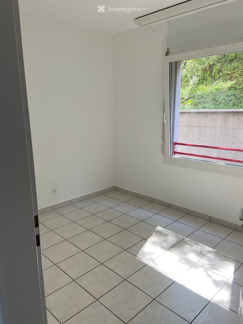 Empty room, white walls, tiled floor, sliding window, balcony access, power outlet on the wall, bright sunlight coming through the window