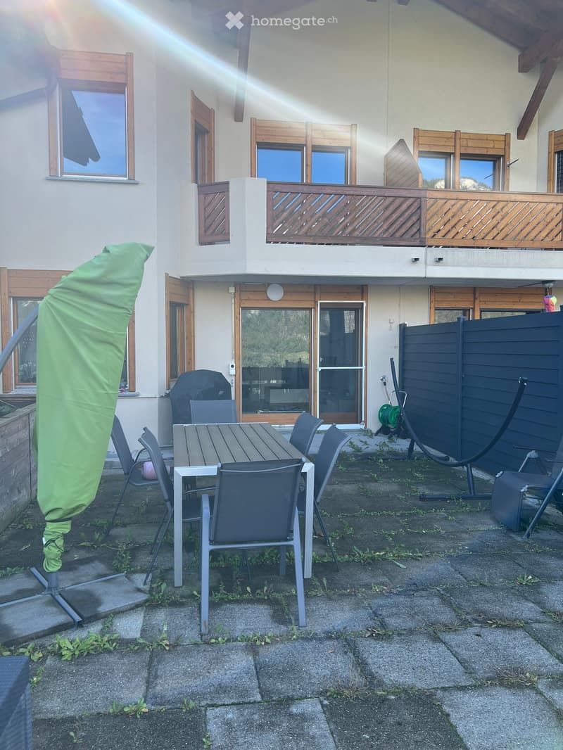 A house with a balcony and a patio with a table and chairs