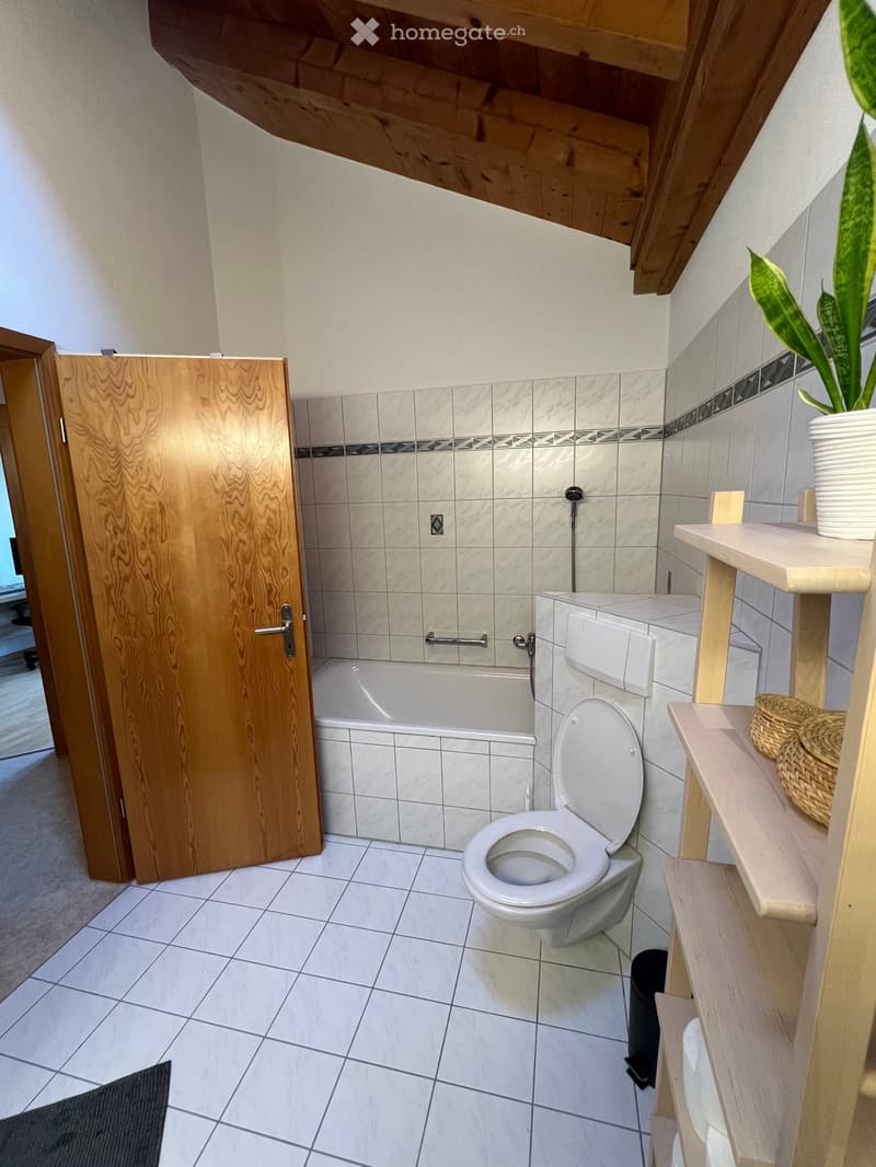 white tiled floor, white walls, wooden ceiling, bathtub, toilet, shelves, plant on shelf
