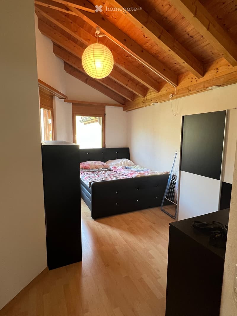 a bedroom with wooden flooring, exposed wooden ceiling, a bed, and a window with a view outside
