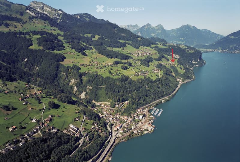 Mountain landscape with a lake, multiple buildings, and a road leading to the lake
