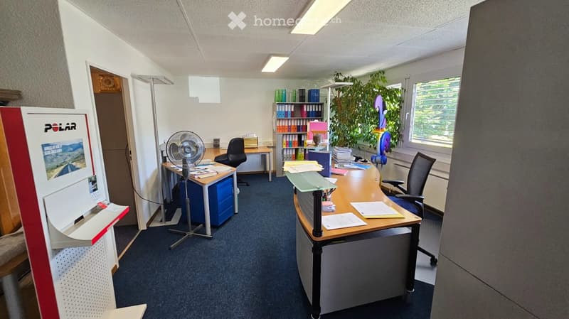 Empty office room with desks, chairs, and bookshelves.