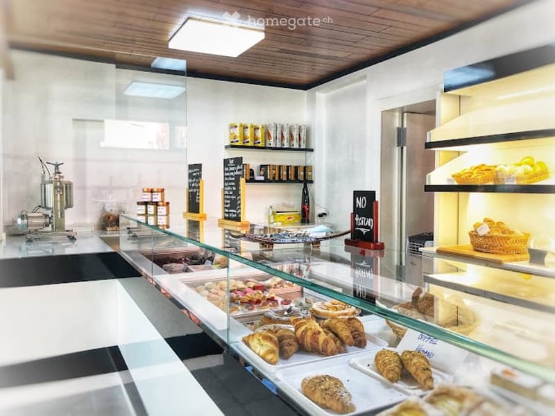 bakery shop with breads, cakes, and pastries on a glass counter, wooden ceiling, white wall, display shelves