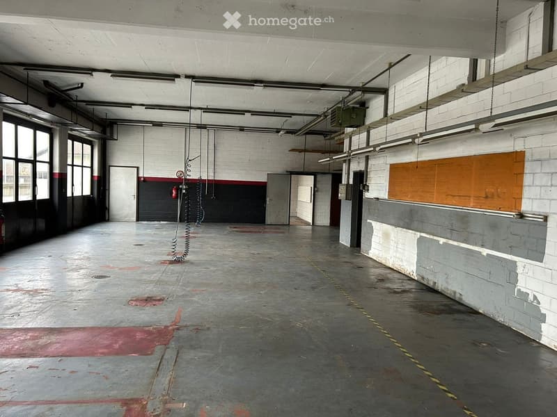 large warehouse, industrial doors, high ceiling, suspended cables, red markings on floor