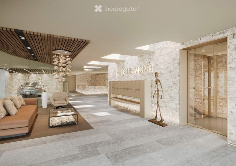 The lobby area has a large open space with light grey flooring and brick walls, a brown sofa, a glass coffee table, a beige chair, and a tall white vase with white flowers. There is a wooden ceiling with modern fixtures, and a large chandelier hanging fro