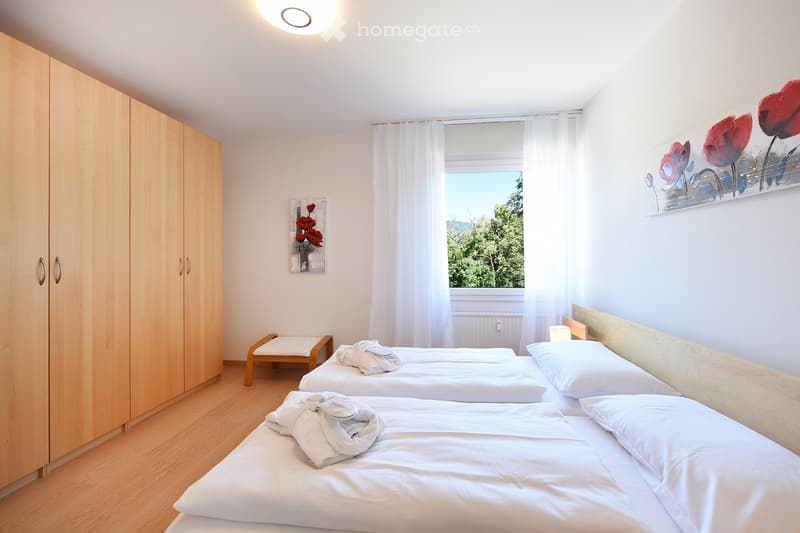Three single beds, a bench, built-in wardrobes, and two paintings on the wall