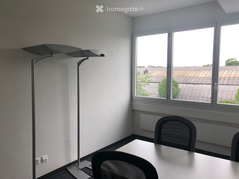 small office room with white walls, floor lamp, white desk, 3 black chairs, large window with view