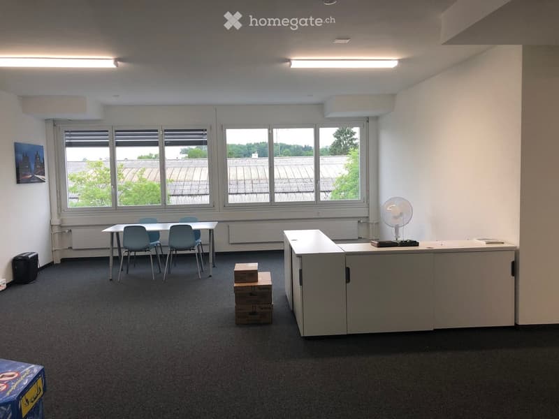 empty office room with long table, 4 chairs, picture, ceiling lamps, floor fan, desk, and boxes