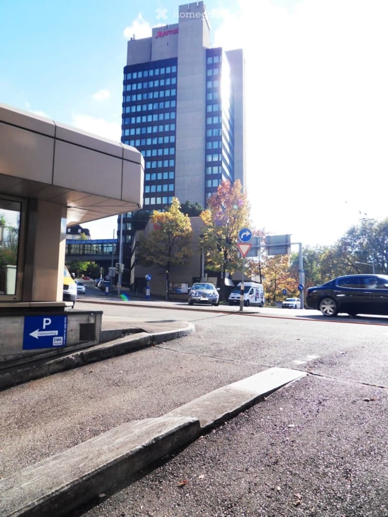Building with glass windows, yellow car, street, streetlights, pedestrian sign, trees, cars moving on road