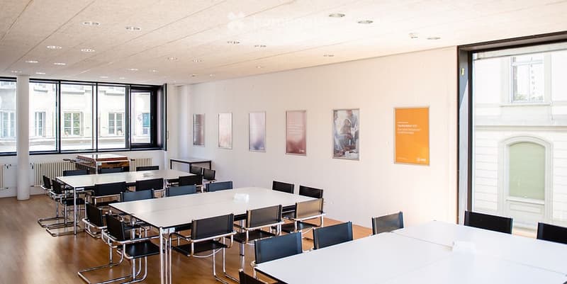 empty conference room with rows of tables and chairs, large windows
