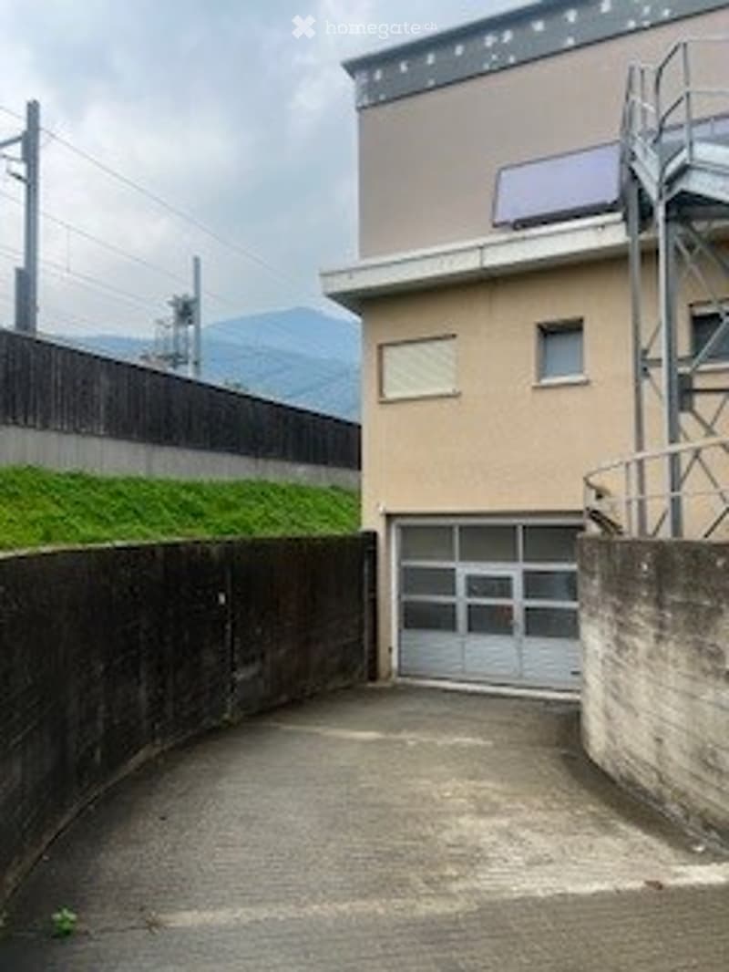 Single story building with a garage, solar panel, green area
