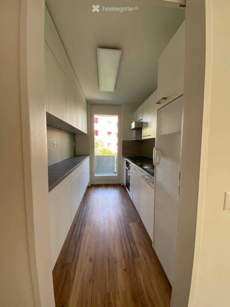 empty kitchen with wooden floor, white cabinets, countertops, sink, dishwasher, countertop, refrigerator