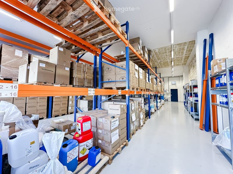Large warehouse filled with neatly organized boxes and containers on racks, with yellow and red cans near the base of one rack.