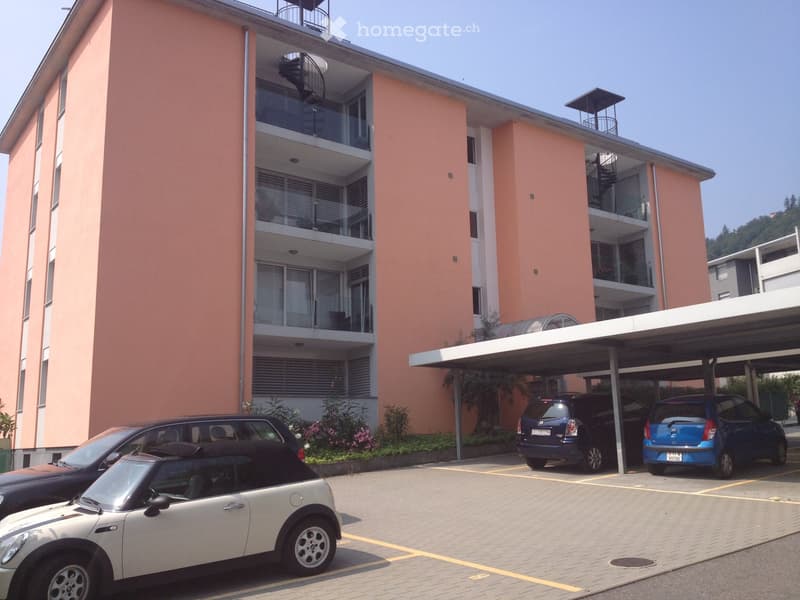 3-storey apartment building with balconies, located in a residential area with parking spaces
