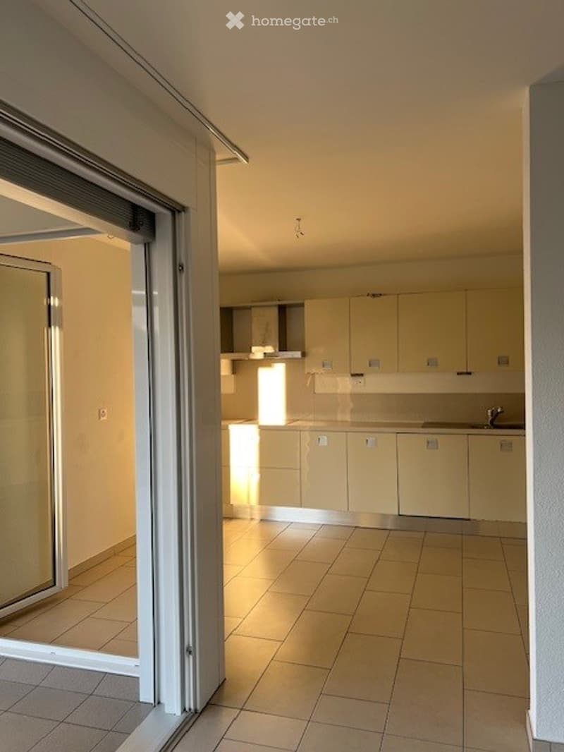 empty kitchen with tiles, white cabinets, a window with light, open glass door