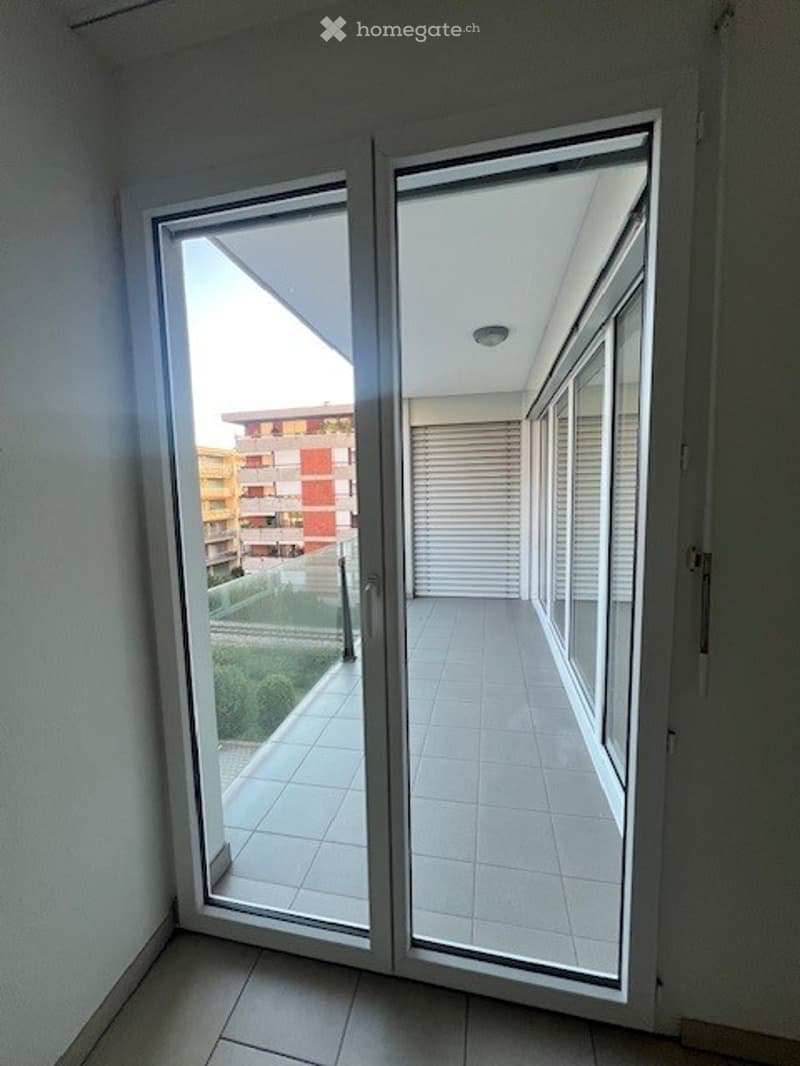 Glass sliding door, balcony, tiled floor, metal railings, and a view of a green landscape