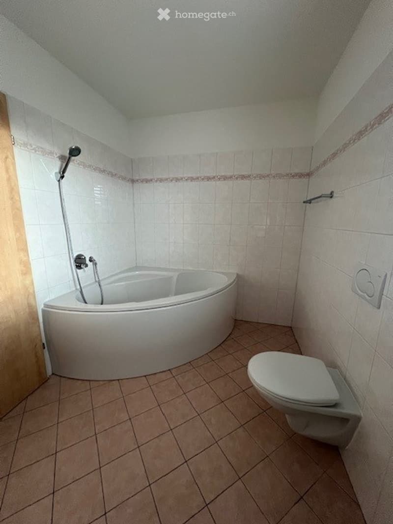 Bathtub, toilet, white walls and tiled floor