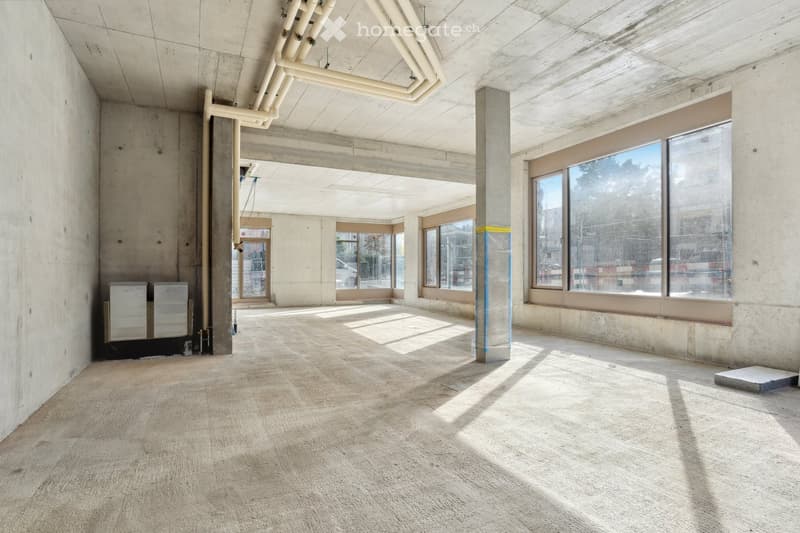 Unfurnished room, concrete walls, wooden floor, large windows, utility pipes on ceiling
