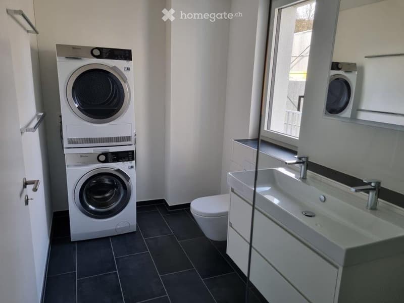 laundry room with a washing machine and a dryer stacked, toilet, sink, cabinet under the sink