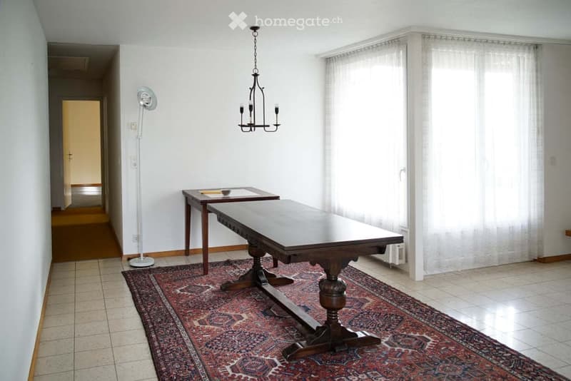 Dining room with wooden tables, chandelier, carpet, white walls, long windows