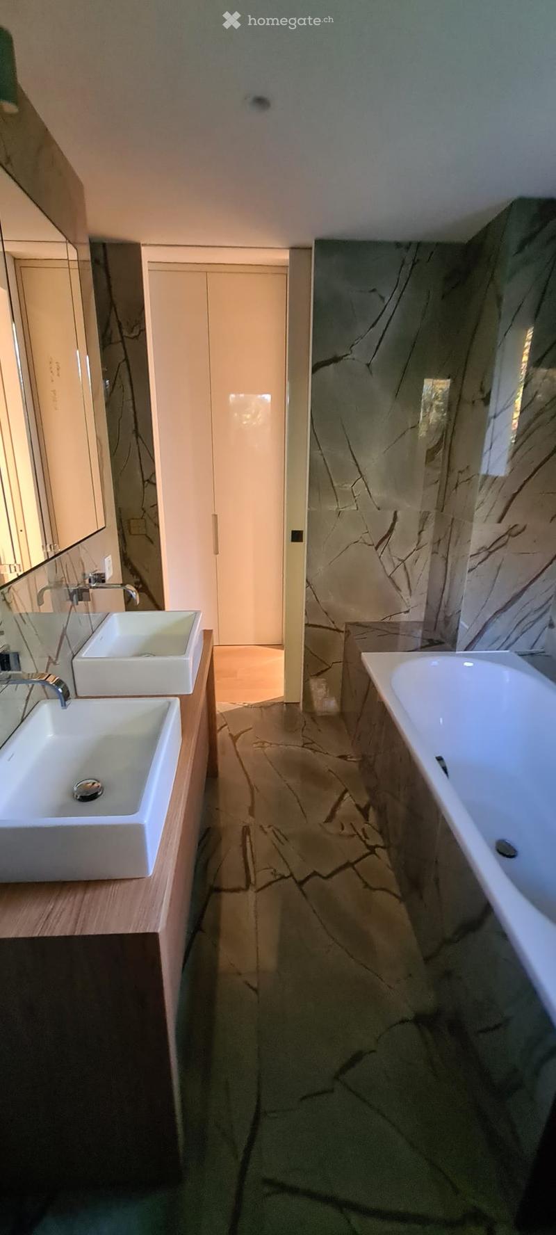 modern bathroom with marble walls, wooden countertops, two sinks, mirror, walk-in shower, bathtub
