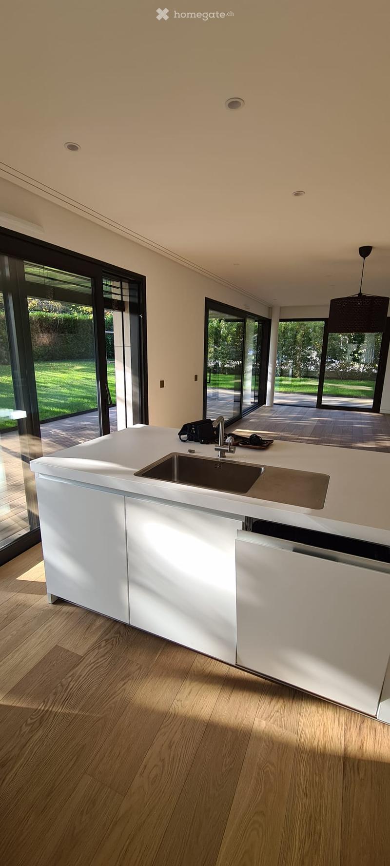 kitchen island with countertop, stainless steel sink, glass doors, wooden floor, sliding glass doors, view of the exterior