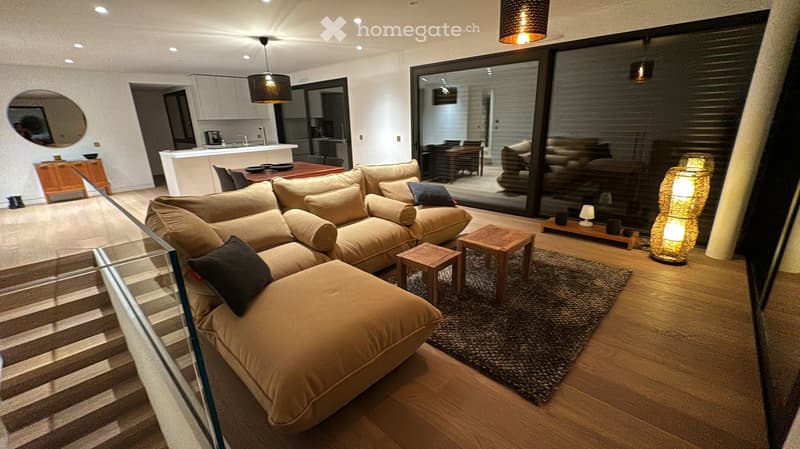 large open living area, corner sofa, wooden floor, two side tables, rug, view to the outside