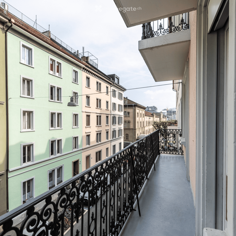 Building, exterior, balcony with black railings, white windows, green building, city view