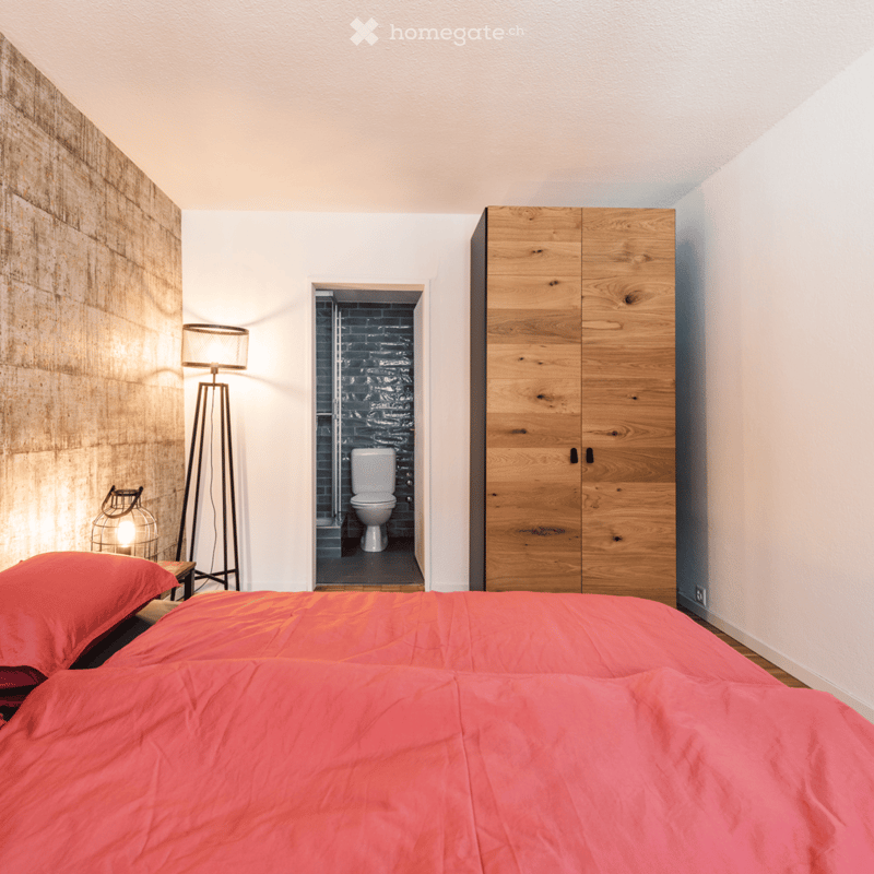 Bedroom with a double bed, nightstand, lamp, wooden wardrobe, and a separate toilet.
