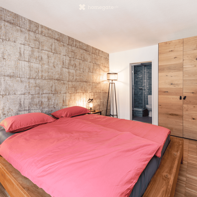 a bed with pink bed sheet, a lamp, and a toilet