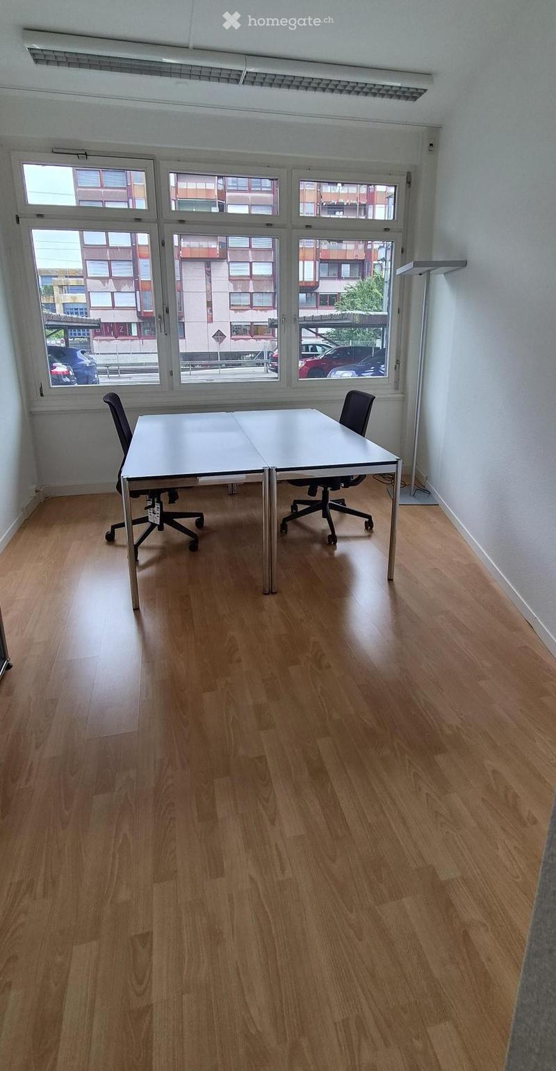 Bright room with wooden flooring, large windows, a white table, and two black chairs.