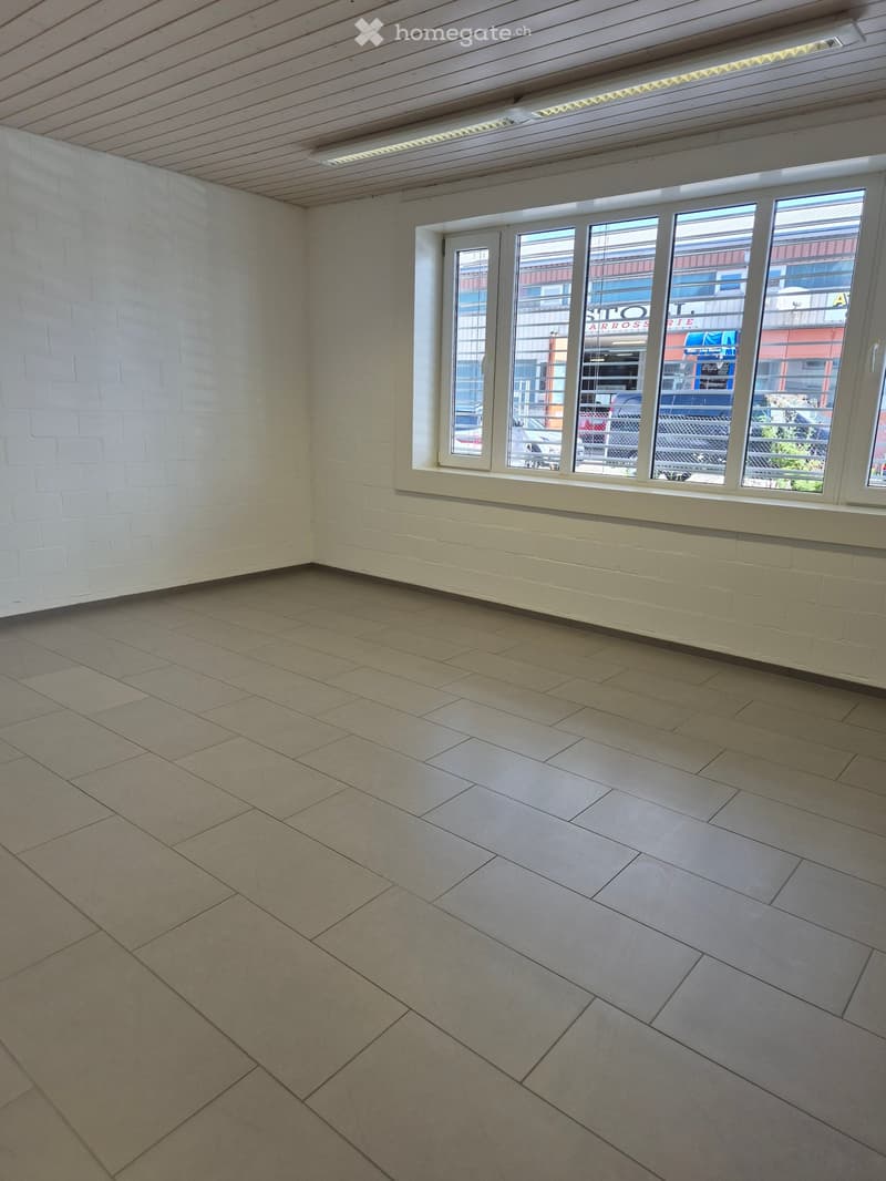 empty room with white tiled floor, white walls, white ceiling with built-in lighting, large window with white shutters, view of street outside