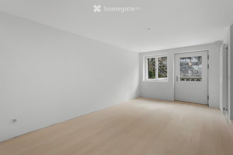 empty room with wooden floors, two windows, power outlet on the wall