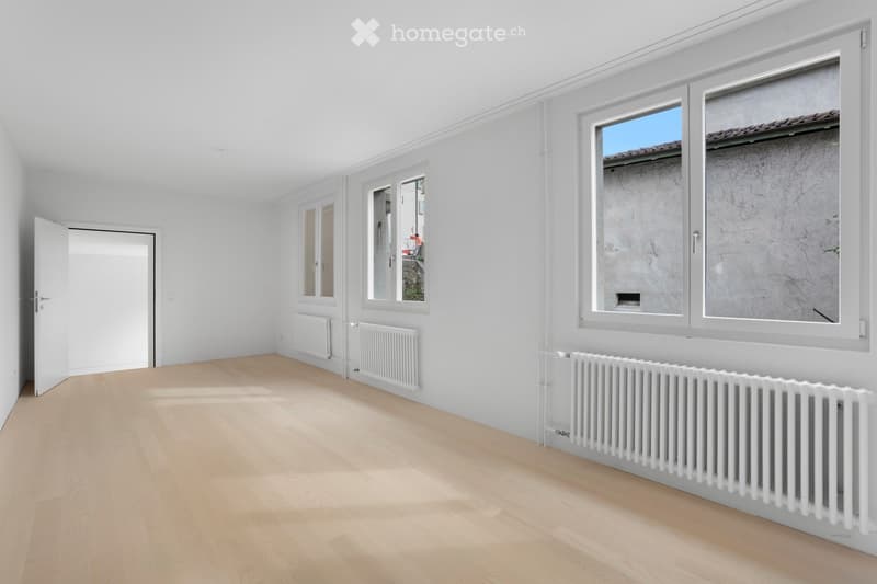 empty room with wooden floors, white walls, large windows with white frames, and radiators
