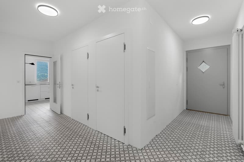 spacious empty room, white walls, geometric tile flooring, large glass window, open door leading to another room