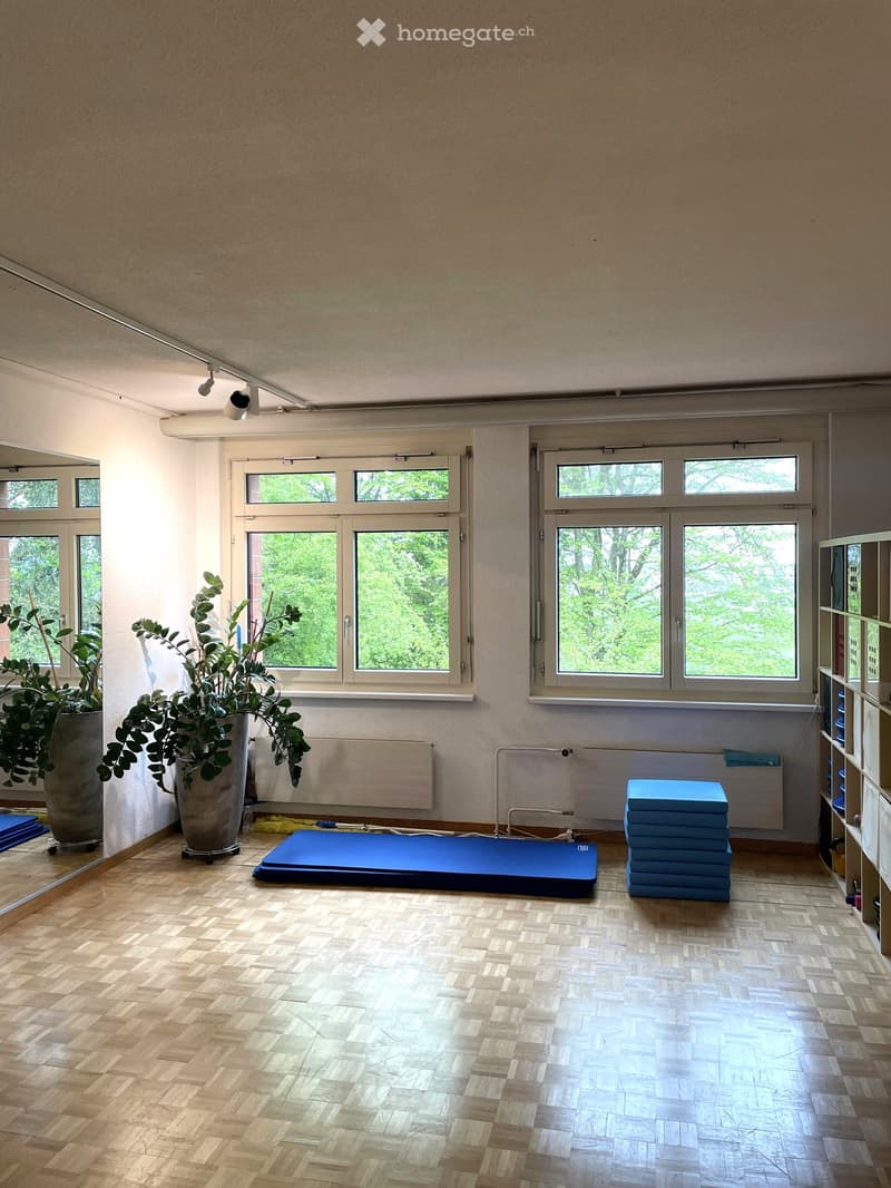 spacious room with wooden floors, large windows, potted plants, yoga mats, storage shelves