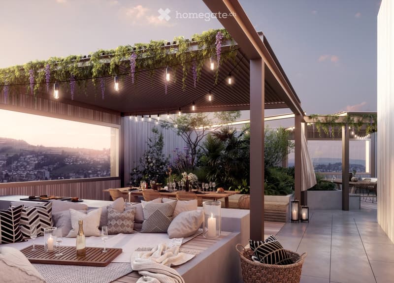 Covered outdoor patio with comfortable seating, string lights, and lush greenery. The space features a panoramic view of the city skyline in the background.