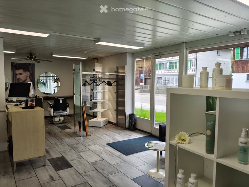 Interior of a store, a reception desk, a monitor, shelves, chairs, desk, mirrors, door, window, rug, table with flower, ceiling fan
