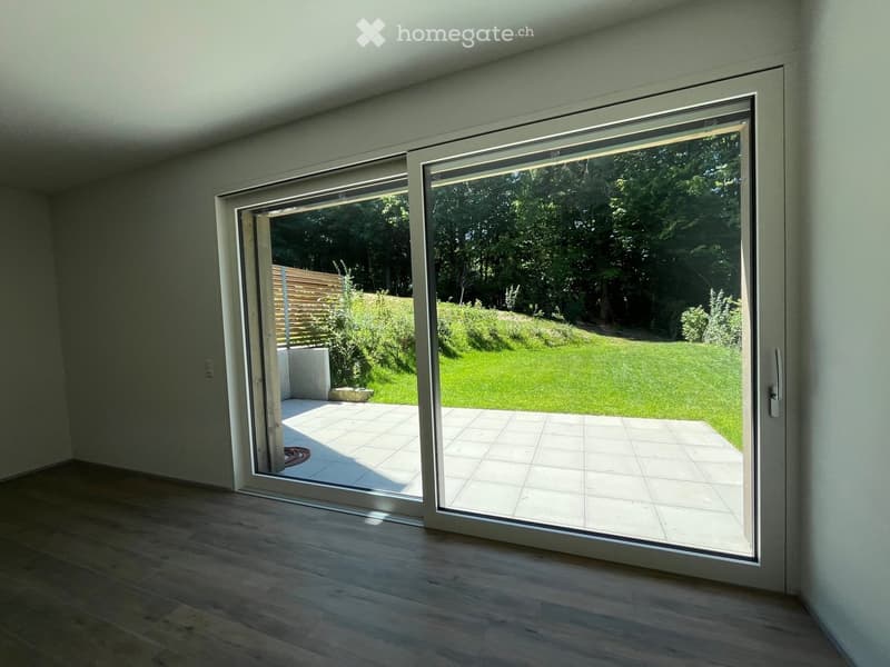 Empty room with large sliding glass doors leading to a tiled patio and a green lawn.
